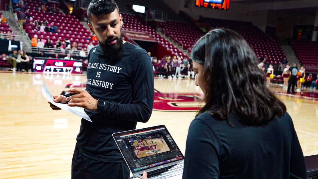 Dans un environnement dynamique au bord du terrain, un membre de l'équipe du Boston College utilise la plate-forme Catapult Pro Video Focus sur un ordinateur portable pour effectuer une analyse vidéo de basket-ball en temps réel. Le flux de travail en direct est en action, illustrant comment l'analyse secondaire instantanée permet aux équipes de prendre des décisions stratégiques rapides.