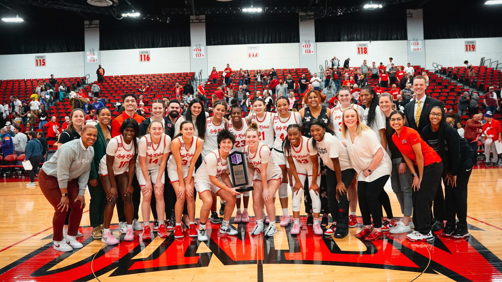 The UNLV Lady Rebels Women's Basketball team proudly gathered on the court, smiling and posing with a championship trophy, exemplifying the team spirit and success that can be achieved through effective use of video analysis and strategic development.