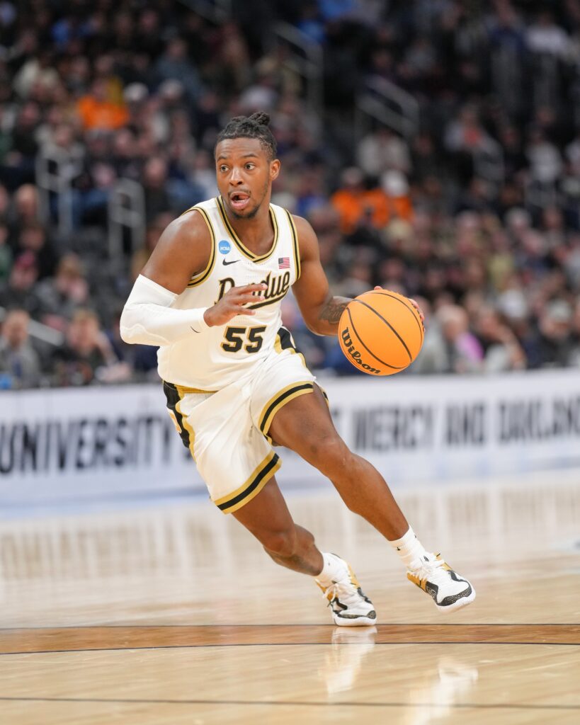 Purdue Boilermakers basketball player number 55 in action, dribbling the ball down the court during a game.