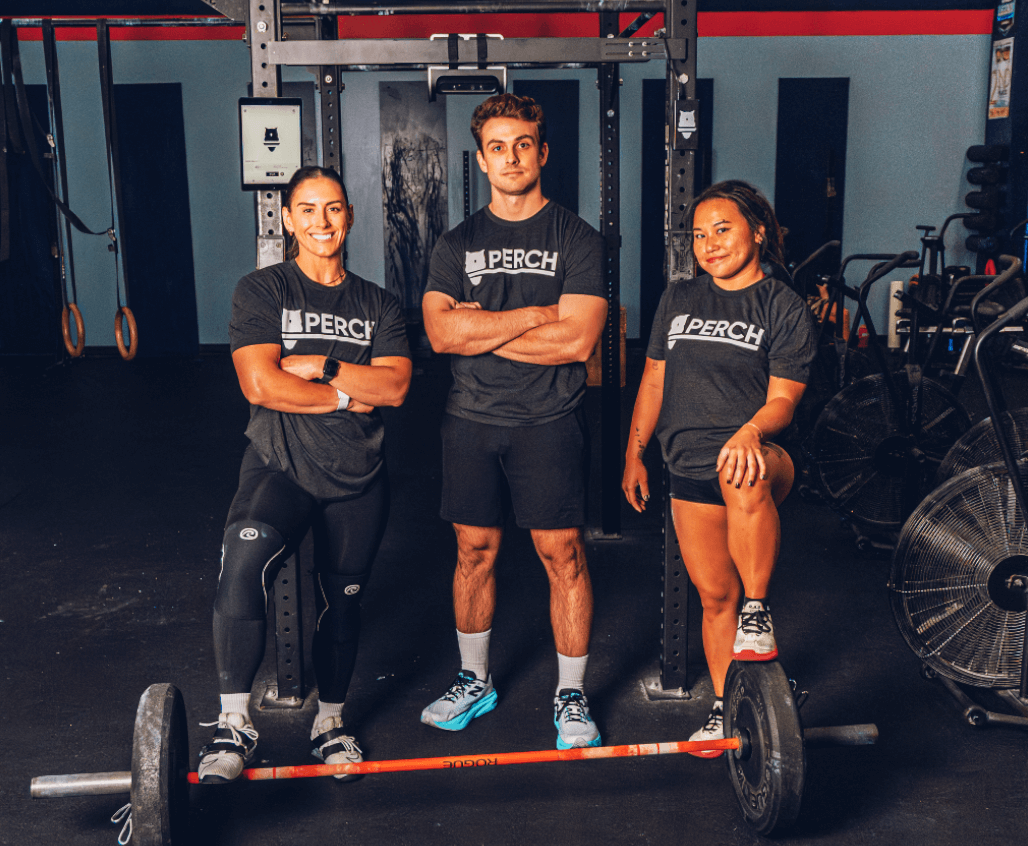 Ba vận động viên tạo dáng trước ống kính trong phòng tập tạ.